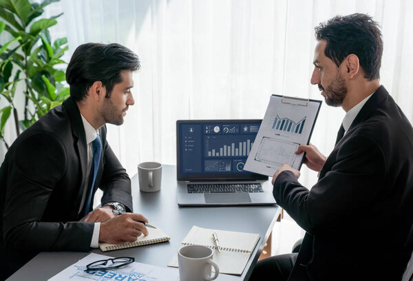 Занятая команда аналитиков обсуждает финансовые данные на цифровой приборной панели, анализирует диаграмму и график с помощью программного обеспечения для передачи данных на экране ноутбука. Бизнес-аналитика и Fintech. Пылкий