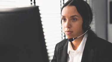 Competent female operator working on computer and talking with clients. Concept relevant to both call centers and customer service offices.