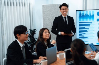 Confidence and asian businessman give presentation on financial analyzed by business intelligence in dashboard report to other people in board room meeting to promote harmony in workplace.