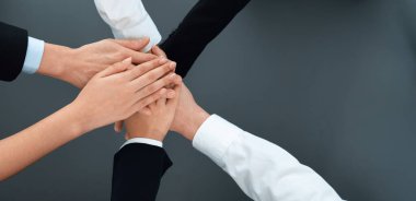 Top view partial hands wearing formal suit joining stack and form circle as symbol of team building, unity and harmony in office workplace. Successful business team of synergy holding hand together.