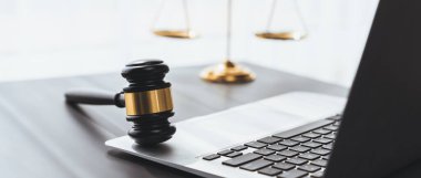 Adalet ve hukuki otoriteyi temsil eden, altın dengeli ölçek ve hukuk bürosunda dizüstü bilgisayarlı tokmak, avukat ve hakimin eşitlik ve adil yargılama kavramını yansıtıyor. denge