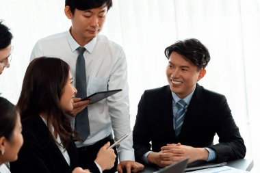 Harmony in office concept as business people analyzing dashboard paper together in workplace. Young colleagues give ideas at manager desk for discussion or strategy planning about project.