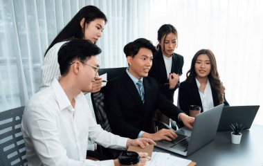 Harmony in office concept as business people analyzing dashboard paper together in workplace. Young colleagues give ideas at manager desk for discussion or strategy planning about project.