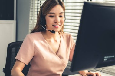 Competent female operator working on computer and while talking with clients. Concept relevant to both call centers and customer service offices.