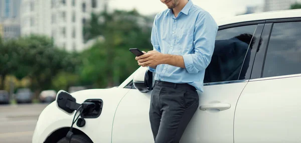 Progressive Businessman Talking Phone Leaning Electric Car Recharging Public Charging — Stockfoto