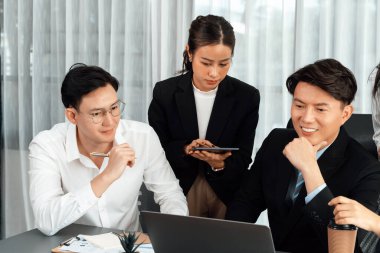 Harmony in office concept as business people analyzing dashboard paper together in workplace. Young colleagues give ideas at manager desk for discussion or strategy planning about project.