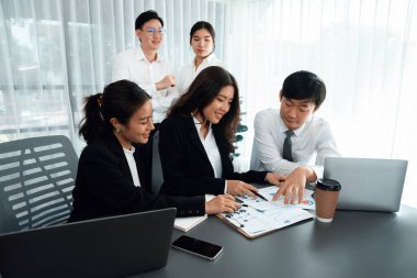 Harmony in office concept as business people analyzing dashboard paper together in workplace. Young colleagues give ideas at manager desk for discussion or strategy planning about project.