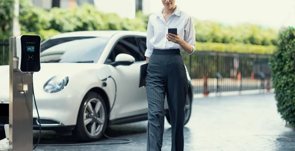 Closeup Businesswoman Using Tablet Walking While Recharging Her Electric Vehicle — Foto de Stock