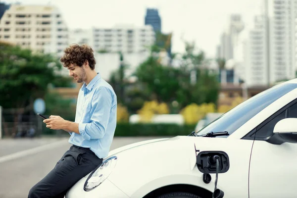 Progressive Businessman Talking Phone Leaning Electric Car Recharging Public Charging — Stock fotografie