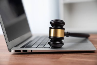 Hukuk firmasında ya da avukatlık bürosunda dizüstü bilgisayarı olan siyah tahta tokmak çekiç avukat ve hakim için adalet ve hukuk sistemi, mahkemelerde otoriteyi ve adaleti simgeler. denge