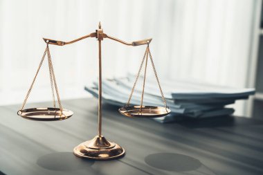 Parlak altın dengeli ölçek ve hukuk bürosundaki yasal kağıt yığını konsept adalet ve hukuki sembol olarak masanın üzerinde. Avukat ve avukatın adil ve eşitlik kararı için terazi uygulayın. denge