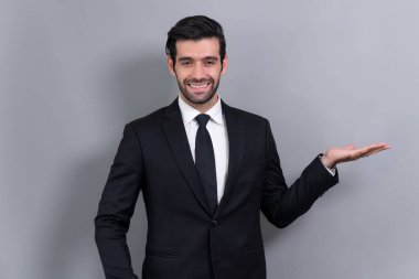 Resmi takım elbiseli kendine güvenen bir işadamı, terfiyi ya da boş alan reklamını göstermek için el ele tutuşuyor. Heyecanlı bir yüz ifadesi ve izole edilmiş bir arkaplanda jest yapıyor. Coşkulu