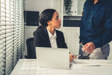 Competent female employee discussing with her colleague, employer using laptop at her office. Interpersonal relations among coworkers.