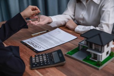 Emlakçı, ev kredisi anlaşmasının başarıyla tamamlanmasının ardından, yeni bir ev hayalinin hayata geçirilmesinin bir simgesi olarak alıcıya anahtarı teslim etti. Coşkulu.