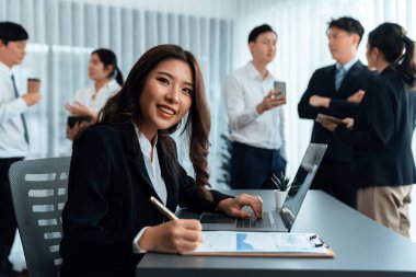 Focus portrait of female manger, businesswoman in the harmony meeting room with blurred of colleagues working together, analyzing financial paper report and dashboard data in background.