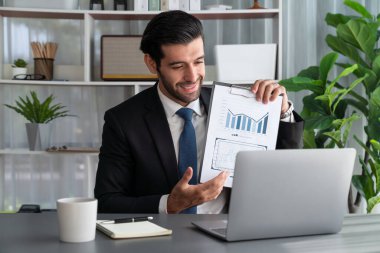 Siyah takım elbiseli profesyonel işadamı, online toplantı sırasında dizüstü bilgisayarla finansal veri ya da BI belgesi sunuyor. Etkili uzaktan çalışmanın sanal toplantı sunumuyla uzaktan çalışma konsepti. Coşkulu