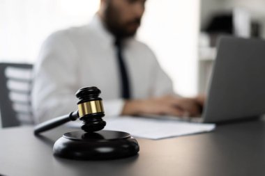 Hukuk bürosunun masasında yasal evraklarla çalışan avukatın bulanık arkaplanına odaklanın. Kanun yapıcı ve avukatın adil ve adil yargılaması için meşru çekiç. Eşitlik
