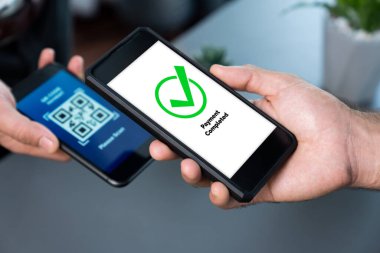 Parasız ödeme taraması için QR kodu ekranda görüntülendi. Kapalı eller, mobil uygulamadan elektronik işlem yoluyla para aktarmak için akıllı telefonu tutuyor. Hızlı ödeme için barkod teknolojisi. Coşkulu