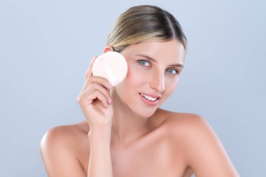 Alluring beautiful female model applying powder puff for facial makeup concept. Portrait of flawless perfect cosmetic skin woman put powder foundation on her face in isolated background.