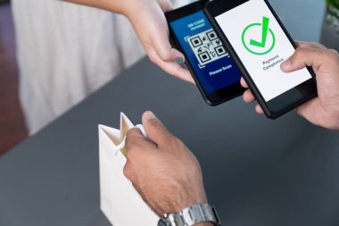 Parasız ödeme taraması için QR kodu ekranda görüntülendi. Kapalı eller, mobil uygulamadan elektronik işlem yoluyla para aktarmak için akıllı telefonu tutuyor. Hızlı ödeme için barkod teknolojisi. Coşkulu