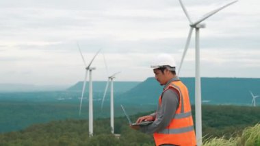 Kırsal kesimdeki bir tepenin tepesinde ya da dağda rüzgar çiftliğinde çalışan bir mühendis. Yenilenebilir ve sürdürülebilir enerjinin gelecekteki üretimi için yenilikçi bir ideal. Rüzgar türbininden enerji üretimi.