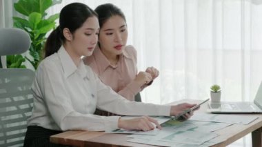 Ofis çalışma alanında birlikte çalışan iki genç hevesli iş kadını. Genç meslektaşlar tartışırken ve dizüstü bilgisayar kullanırken. Modern ofis çalışanları masada birlikte oturuyorlar..