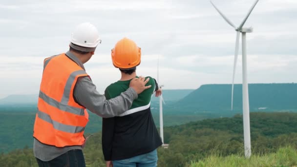 田舎の丘や山の上の風力発電所で彼の息子とエンジニア 再生可能エネルギー 持続可能なエネルギーの将来の生産のための進歩的な理想 風力タービンからの発電 — ストック動画
