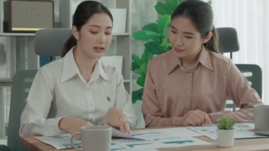 Ofis çalışma alanında birlikte çalışan iki genç hevesli iş kadını. Genç meslektaşlar tartışırken ve dizüstü bilgisayar kullanırken. Modern ofis çalışanları masada birlikte oturuyorlar..