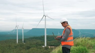 Kırsal kesimdeki bir tepenin tepesinde ya da dağda rüzgar çiftliğinde çalışan bir mühendis. Yenilenebilir ve sürdürülebilir enerjinin gelecekteki üretimi için yenilikçi bir ideal. Rüzgar türbininden enerji üretimi.