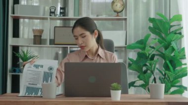 Ofiste çalışan ve dizüstü bilgisayar yazan hevesli bir iş kadını. Masasında oturmuş laptopla çalışan güzel bir ofis hanımı..