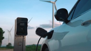 Çevreyi korumak için rüzgar türbininden yeşil ve yenilenebilir enerjiyle çalışan şarj istasyonunda şarj edilen gelişmiş gelecek enerji altyapısı konsepti.