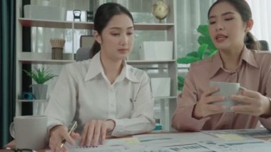 Ofis çalışma alanında birlikte çalışan iki genç hevesli iş kadını. Genç meslektaşlar tartışırken ve dizüstü bilgisayar kullanırken. Modern ofis çalışanları masada birlikte oturuyorlar..