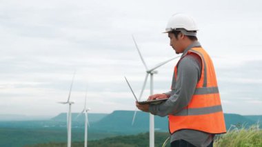 Kırsal kesimdeki bir tepenin tepesinde ya da dağda rüzgar çiftliğinde çalışan bir mühendis. Yenilenebilir ve sürdürülebilir enerjinin gelecekteki üretimi için yenilikçi bir ideal. Rüzgar türbininden enerji üretimi.