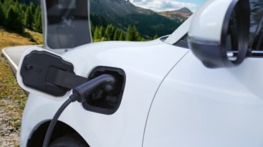 Tepe yolundaki şarj istasyonunda elektrikli arabanın çevresel farkındalığı için yenilikçi bir kavram. EV araba temiz çevre için yenilenebilir enerjiden güç alıyor.