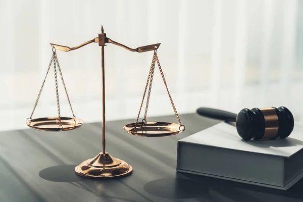 Symbolizing justice and legal authority, golden balanced scale and gavel on desk with law book in lawyer office background, reflecting concept of equality and fair judgment. equility