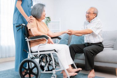 A contented senior couple and their in-home nurse. Elderly female in wheelchair with her young caregiver.
