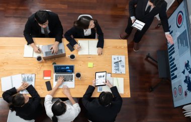 Top view manager or office worker give presentation in harmony conference room to business colleague, BI data dashboard on screen and pile of financial analyzed data reports on meeting table.