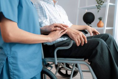 Caring nurse and a contented senior man in a wheel chair at home, nursing house. Medical for elderly patient, home care for pensioners.