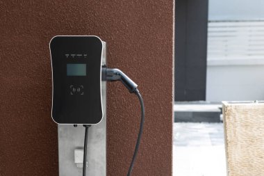 Progressive green energy-powered charging station concept for electric vehicle connected to home charging station at the garage or backyard. Eco friendly rechargeable car powered by clean energy.