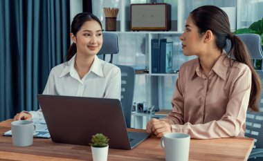 Modern ofis çalışma alanında iş birliği yapan iki genç ofis çalışanı, modern ofis çalışanı olarak profesyonelliklerini sergileyerek, dizüstü bilgisayarda tartışıyorlar ve birlikte çalışıyorlar. Coşkulu.