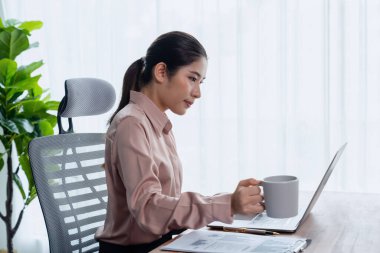 Genç Asyalı iş kadını, elinde bir fincan kahveyle modern ofis çalışma alanına not alarak, çekici ve çalışkan bir ofis hanımı olarak profesyonelliğini gösteriyor. Coşkulu.
