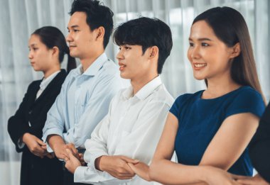 Mutlu ve gülümseyen çok ırklı ofis çalışanı, sinerjiyi ve ticari başarı için işbirliğini destekleyen bir kuyrukta el ele tutuşuyor. Modern işyerinde çeşitli profesyonel ofis çalışanları arasında bağ var. Uyum