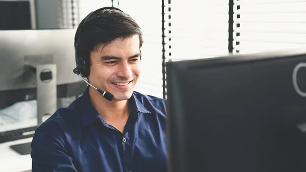 Young competent asian male call center agent working at his computer while simultaneously speaking with customers. Concept of an operator, customer service agent working in the office with headset.