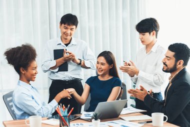 Çeşitli iş arkadaşları başarıyı şirket işyerindeki el sıkışma ve takım çalışmasıyla kutluyor. Çok kültürlü, mutlu profesyonellerden oluşan bir ekip ofiste tokalaşarak birlik oldular. Uyum