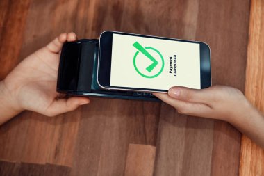 QR kodu parasız ödeme taraması için ekranda gösterilir. Kapalı eller, mobil uygulamadan elektronik işlem yoluyla para aktarmak için akıllı telefonu tutuyor. Hızlı ödeme için barkod teknolojisi. Coşkulu.