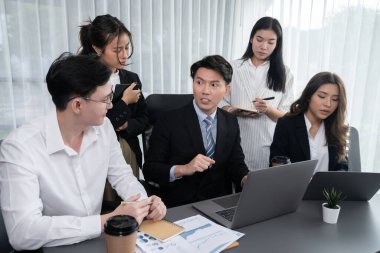 Harmony in office concept as business people analyzing dashboard paper together in workplace. Young colleagues give ideas at manager desk for discussion or strategy planning about project.