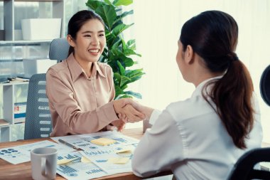İki Asyalı iş kadını, iş yeri konseptinde takım çalışması ve dürüstlüğün önemi olarak, gösterge paneli veri kağıtlarının yığınlarını başarıyla analiz ettikten sonra modern ofiste el sıkışıyor. Coşkulu.