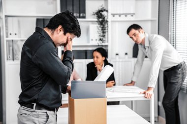 Depressed and disappointed employee packing his belongings after being fired for not being competent. Gossiped by his colleagues behind his back. Layoff due to economic depression.