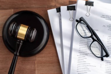 Yakın plan siyah tahta tokmak çekiç ve ahşap ofis masasının arka planındaki yasal belge avukat ve hakim için adalet ve hukuk sistemi, yasal otorite ve mahkemelerde adalet. denge