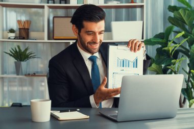 Siyah takım elbiseli profesyonel işadamı, online toplantı sırasında dizüstü bilgisayarla finansal veri ya da BI belgesi sunuyor. Etkili uzaktan çalışmanın sanal toplantı sunumuyla uzaktan çalışma konsepti. Coşkulu